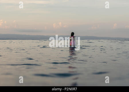 Zurück Blick auf die Silhouette der weiblichen Surfer sitzen auf Surfbrett im Wasser Stockfoto