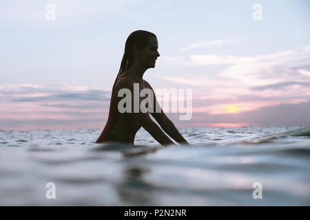 Silhouette einer Frau ruht auf Surfen im Ozean auf Sonnenuntergang Stockfoto