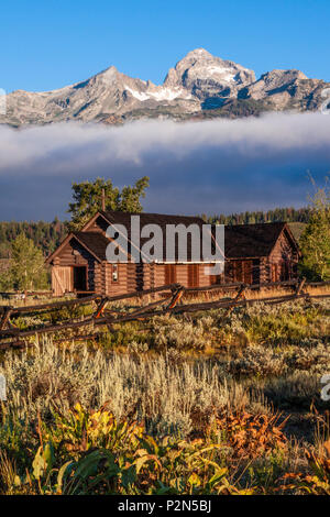 Grand Teton Bergkette und den bischöflichen Kapelle der Verklärung bei Sonnenaufgang, am frühen Morgen Licht getaucht mit Nebel und tiefliegenden Wolken. Stockfoto