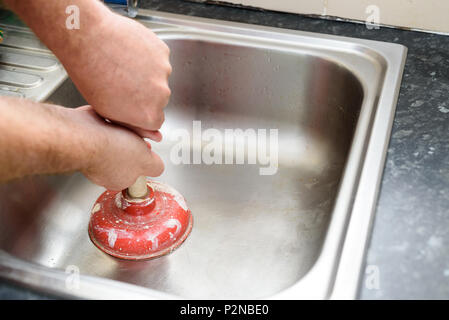 Mann hält ein Kolben mit zwei Händen und kein Wasser im Waschbecken, verwendet zum Reinigen verstopfter/blockierte Spülbecken Stockfoto