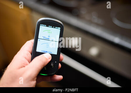 Mann mit einem inländischen Energy Smart Meter Einheit in der Küche und zeigt Ihren Energieverbrauch in Echtzeit Stockfoto