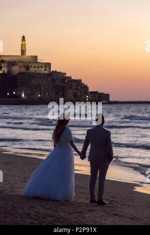 Israel, Tel Aviv, dem Strand, den Sonnenuntergang über der Altstadt von Jaffa, jungvermählte Paar beobachten die Sonne Stockfoto