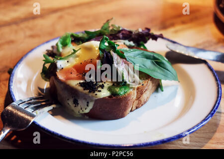Bruschetta mit pochiertem Ei und Grünen auf dem Tisch im Cafe Stockfoto