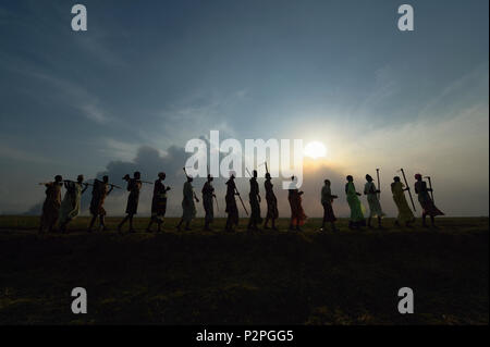 Nach Zusammenarbeit in einer Gemeinschaft garten, Frauen singen und tanzen wie Sie in Dong Boma, Südsudan zu Fuß, auf einem Deich diese aufgebaut. Stockfoto