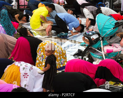 Manila, Philippinen. 2 Feb, 2018. Muslime im Gebet niederwerfen, während ein Junge auf aussieht. Filipino und ausländische Muslime versammeln sich Quirino Tribüne in Manila zum Ende des Ramadan zu feiern. Sie feiern es mit Gebeten, Essen und Spaß, vor allem für die Familie. Eid al-Adha, hat keine bestimmte Zeitdauer und ist ein wichtiger religiöser Feiertag von Muslimen weltweit, die das Ende des Fastenmonats Ramadan, der islamischen heiligen Fastenmonat Markierungen gefeiert. Credit: Josefiel Rivera/SOPA Images/ZUMA Draht/Alamy leben Nachrichten Stockfoto