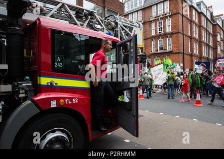 London, Großbritannien. 16 Juni, 2018. Ein Feuerwehrmann stoppt, um Solidarität mit Hunderten von Menschen, die an einer Gerechtigkeit für Grenfell Solidarität März von Downing Street das Home Office und zurück organisiert von Gerechtigkeit 4 Grenfell und den Feuerwehren Union zwei Tage nach dem ersten Jahrestag der Grenfell Turm Brand, bei dem 72 Menschen starben und mehr als 70 wurden verletzt. Stockfoto