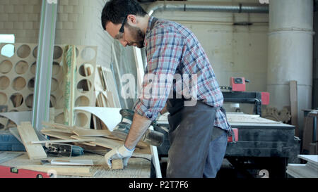 Junge Tischler arbeiten mit elektrischen Maschine in der Werkstatt Stockfoto