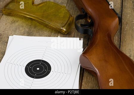 Schießen und pneumatische Waffe. Schild und Hits mit Blei Kugeln auf einem Holztisch. Der dunkle Hintergrund. Stockfoto