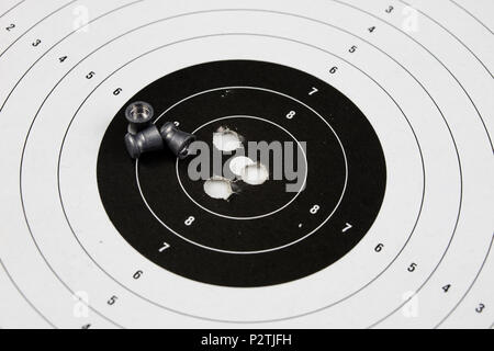 Schießen und pneumatische Waffe. Schild und Hits mit Blei Kugeln auf einem Holztisch. Der dunkle Hintergrund. Stockfoto