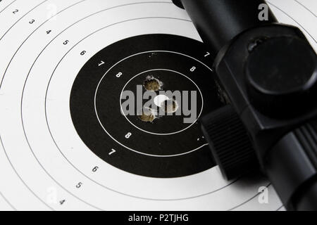 Schießen und pneumatische Waffe. Schild und Hits mit Blei Kugeln auf einem Holztisch. Der dunkle Hintergrund. Stockfoto