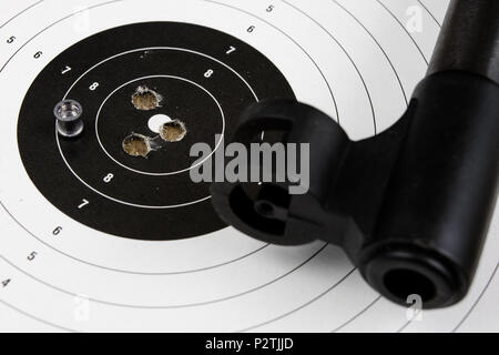 Schießen und pneumatische Waffe. Schild und Hits mit Blei Kugeln auf einem Holztisch. Der dunkle Hintergrund. Stockfoto
