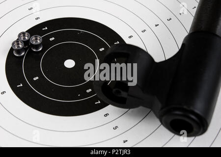Schießen und pneumatische Waffe. Schild und Hits mit Blei Kugeln auf einem Holztisch. Der dunkle Hintergrund. Stockfoto