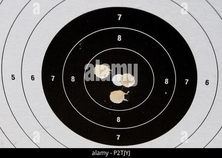 Schießen und pneumatische Waffe. Schild und Hits mit Blei Kugeln auf einem Holztisch. Der dunkle Hintergrund. Stockfoto