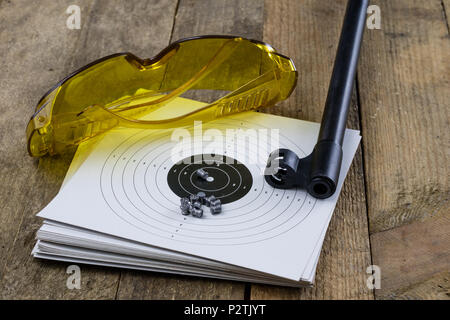 Schießen und pneumatische Waffe. Schild und Hits mit Blei Kugeln auf einem Holztisch. Der dunkle Hintergrund. Stockfoto
