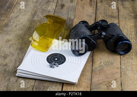 Schießen und pneumatische Waffe. Schild und Hits mit Blei Kugeln auf einem Holztisch. Der dunkle Hintergrund. Stockfoto