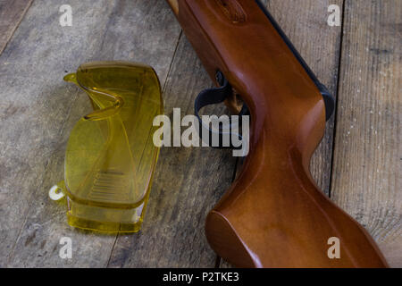 Schießen und pneumatische Waffe. Schild und Hits mit Blei Kugeln auf einem Holztisch. Der dunkle Hintergrund. Stockfoto