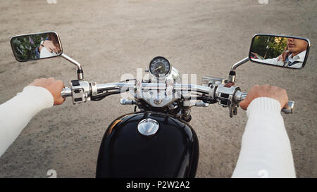 Guy's Händen halten Motorrad CONTROL-Knöpfen zu schließen. In Rückspiegel Reflexion von Gesicht und der Frau die Hand auf die Schulter. Paar auf Reise. Stockfoto