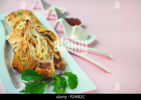 Wraps mit Huhn, Avocado, Koriander und Käse. Chicken burrito auf einem weißen langen Platte mit Rucola und Sauce. Stockfoto