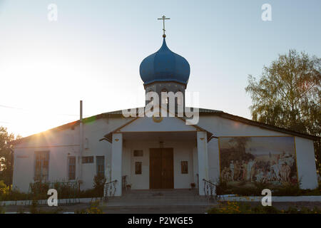 Die christliche Kirche mit einem goldenen Kreuz und ein Blau - Blue Dome im Dorf mit einem Fresko an der Wand am frühen Morgen Sonne Stockfoto