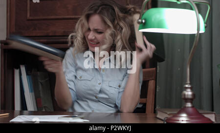 Junge Frau verrückt an ihrem Arbeitsplatz und Tanzen mit Bücher nach einem langen Projekt Stockfoto