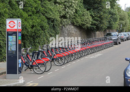 Eine lange Linie der Santander-branded Fahrräder in einer Dockingstation in der Nähe von Wandsworth Town Bahnhof im Südwesten von London, Großbritannien Stockfoto