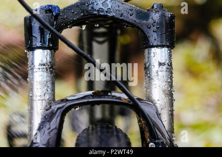 Waschen schmutziger Mountainbike Federgabel Nach dem Reiten bei schlechtem Wetter. Nässe, Schmutz und Öl Flecken an den Beinen der Mountainbike Gabel Stockfoto