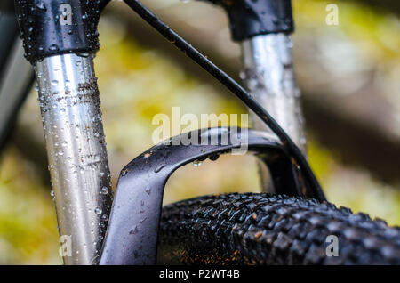 Waschen schmutziger Mountainbike Federgabel Nach dem Reiten bei schlechtem Wetter. Nässe, Schmutz und Öl Flecken an den Beinen der Mountainbike Gabel Stockfoto