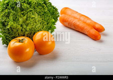 Frisches Gemüse auf einem weißen Holz- Hintergrund. Kopieren Sie Platz. Salat. Gelbe Tomaten und Karotten Stockfoto