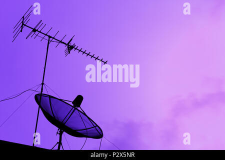 Fernsehen Antenne und Satellitenschüssel für Kommunikation Broadcast auf dem Dach mit Sonnenuntergang Himmel, Dämmerung, silhouette lila Hintergrund, Effekt lig Stockfoto