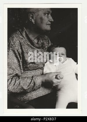 Die tschechoslowakische SOZIALISTISCHE REPUBLIK - circa 1970 s: Vintage Foto zeigt Großmutter wiegen todlder mit Dummy. Retro Schwarz/Weiß-Fotografie. Stockfoto