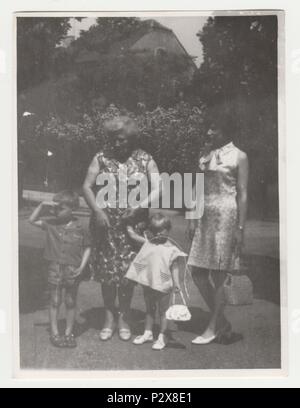 Die tschechoslowakische SOZIALISTISCHE REPUBLIK - circa 1970 s: Vintage Foto zeigt Mutter und Großmutter mit den Kindern im Freien. Retro Schwarz/Weiß-Fotografie. Stockfoto