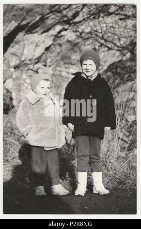 Die tschechoslowakische SOZIALISTISCHE REPUBLIK - circa 1950s: Vintage Foto zeigt kleine Kinder stehen im Freien im Winter. Retro Schwarz/Weiß-Fotografie. Stockfoto