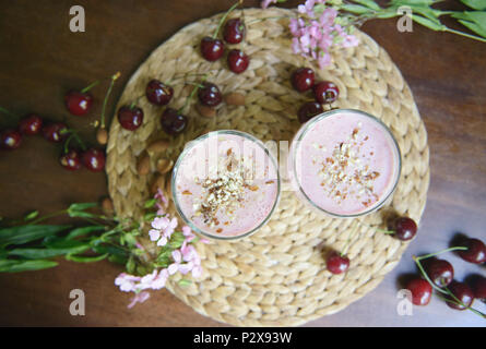 Zwei Gläser mit einem schönen Cherry Smoothies mit Nüsse auf dem Tisch. Ansicht von oben Stockfoto