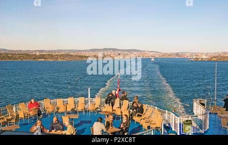 OSLO, Norwegen - 12 April 2010: Passagiere auf der Fähre Segeln von Oslo nach Dänemark. Auf dem Hintergrund ist Küste von Oslo Stockfoto