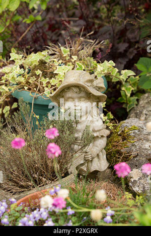 Eine steinerne Figur eines Jungen in der Nähe eines Gartenteiches neben einem Topf Thymian. Lancashire North West England UK GB Stockfoto