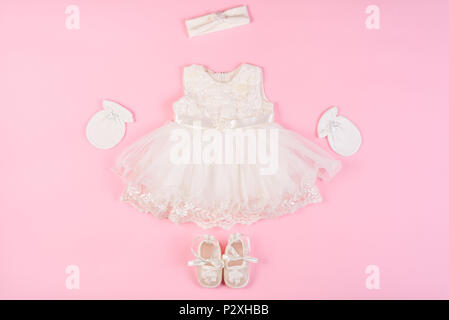 Schönes baby Kleid mit füßlinge und Handschuhe auf einem rosa Hintergrund isoliert Stockfoto
