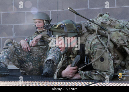 Ein Soldat von Charlie Company 1st Battalion, 125Th Infanterie Regiment in Wyoming, Michigan und Soldat aus dem Lettischen Landstreitkräfte Infanterie Brigade Combat Support Bataillons, offene Kommunikation und Relais Signale von Luft-zu-Boden während urban Operations Training im Camp Äsche gemeinsame Manöver von Training Center kombinierte Waffen kollektive Training Service als Teil der Übung Northern Strike Aug 8, 2016. Die Ausbildung umfasste taktischen Bewegungen, Sicherheit, gegen Türen, Clearing Zimmer und eine Vielzahl von anderen Schlacht Bohrer. Übung Northern Strike 16 ist eine nationale Gua Stockfoto