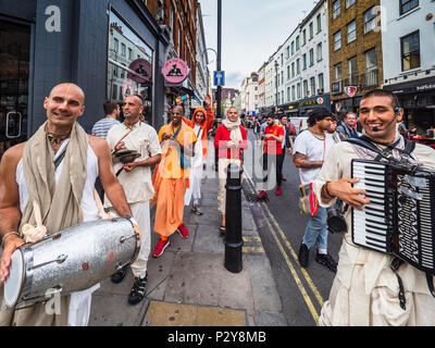 Hare Krishna Chanters bewegen sich durch Old Compton Street im Londoner Stadtteil Soho austeilen lädt kostenlos Essen im Radha Krishna Tempel. Stockfoto