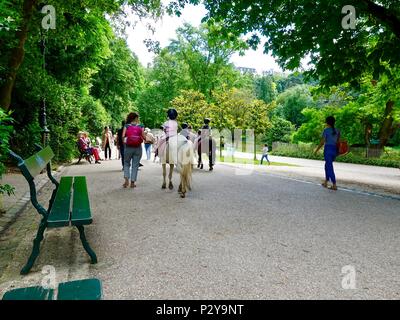 Kinder reiten Ponys an einem warmen Samstag Nachmittag am Parc Buttes Chaumont im Nordosten von Paris, Frankreich Stockfoto