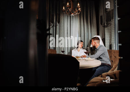 Ein Mann gibt ein Geschenk zu seiner Freundin auf ein Date in einem Restaurant Stockfoto