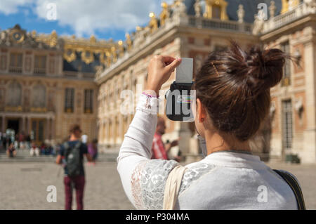 Weibliche Besucher im Chateau de Versailles, an einem hellen, sonnigen Tag, nimmt ein Foto in einem Poloraid instant Kamera. Stockfoto