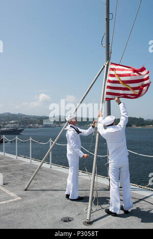 160817-N-WA993-029 YOKOSUKA, Japan (17. August 2016) Luftfahrt Boatswain Mate (Handling) Airman Joshua Schuster aus Simi Valley, Kalifornien, senkt die erste Marine-Jack-Flagge als Luftfahrt Boatswain Mate (Handling) Airman Taylor Sloan aus Portland, Oregon, fängt die Flagge auf dem Flugdeck der Marine nur vorwärts bereitgestellt Flugzeugträger USS Ronald Reagan (CVN-76), nachdem das Schiff zum Board of Inspection und Umfrage (Mission) testen in Gang kommt. Am 22. Mai 2002, ordnete der US-Marine die Flagge, um auf allen angezeigt werden US Navy Schiffe während der globale Krieg gegen den Terrorismus. "Wir müssen s Stockfoto