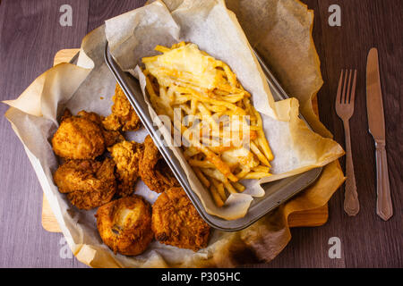 Fast food Essen auf dem Tisch. Fleisch und Pommes frites in der Nahrung. Ungesunde Nahrung in der Papier-Boxen. Hühnerfleisch mit Kartoffeln. Fried schicke Stockfoto