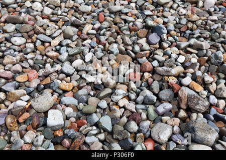 Hintergrund aus kleinen Steinen am Strand. Dekoration aus bunten Steinen. Bunte Steine, der am Ufer des Meeres. Zusammenfassung Hintergrund mit der Natur. Stockfoto