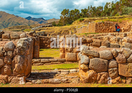 Einer indigenen Quechua Paar in der Inka-ruinen von Chincheros mit einem dramatischen Himmel im Hintergrund in der Nähe der Stadt Cusco, Peru, Südamerika. Stockfoto