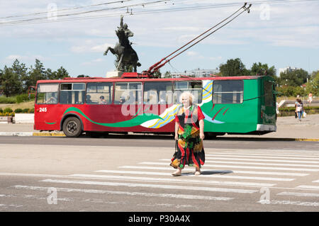 25.08.2016, Tiraspol, Transnistrien, Obus in der transnistrischen Region der Republik Moldau - Farben, ältere Dame in farblich passenden Kleid kreuze Zebras auf dem zentralen Mai Stockfoto