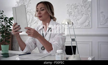 Junge Ärztin sprechen von scype auf Tablet mit Patient im Amt. Stockfoto