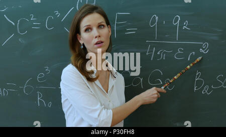 Lehrer im Klassenzimmer auf blackboard Hintergrund erklären, etwas in phisics. Stockfoto