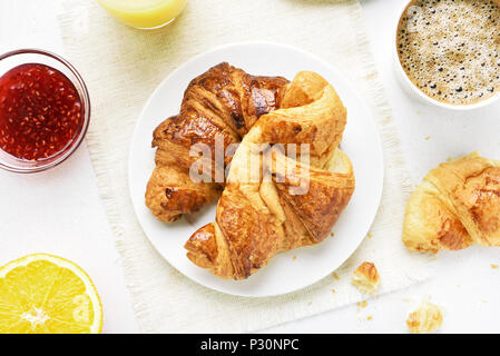 Leckeres Frühstück mit Croissants, Orangensaft, Himbeer Marmelade, Kaffee. Ansicht von oben, flach Stockfoto