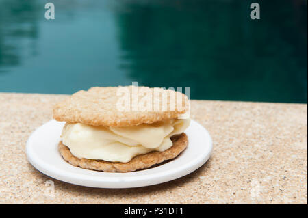 Vanilla Ice Cream Sandwich mit Coconut oatmeal Cookies auf einer weißen Platte am Pool Stockfoto